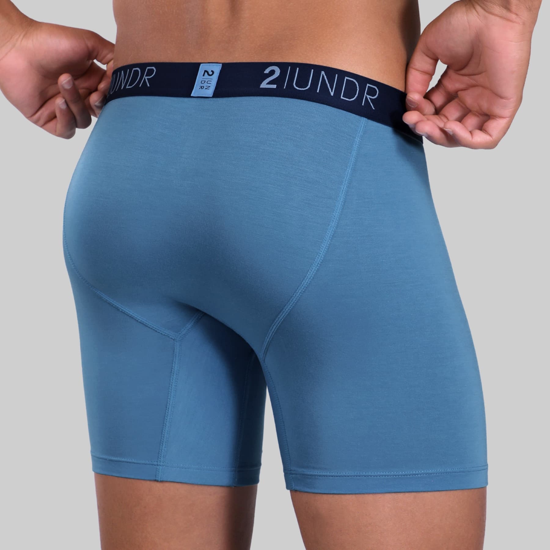 Rear view of a model wearing blue 2UNDR Swing Shift boxer briefs